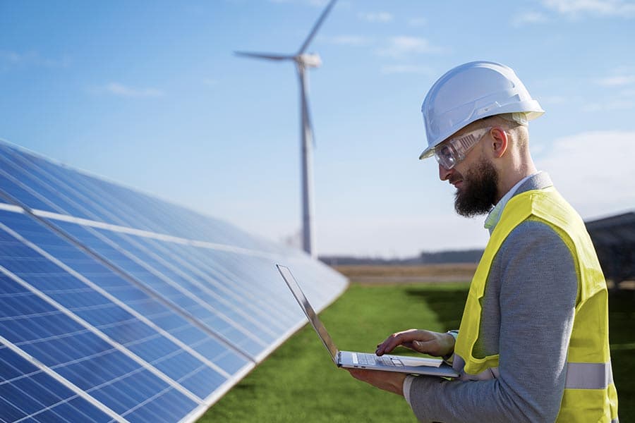 Technician monitoring solar panel performance on a laptop